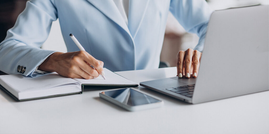 persona trabajando en un escritorio con un ordenador y papeles alrededor